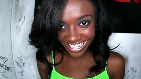 Black chick is teasing a large dick in a glory hole and she smiles